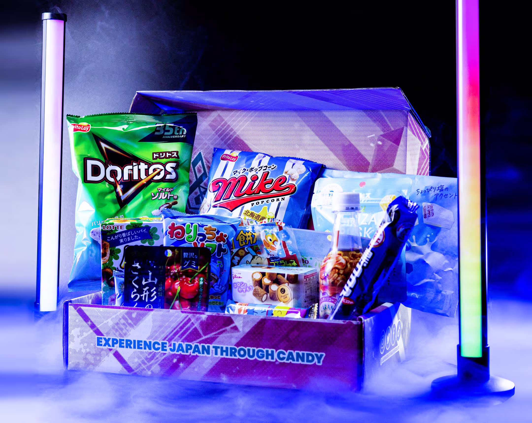 A box overflowing with Japanese snacks, the background features fluorescent lights and smoke circling around the product.