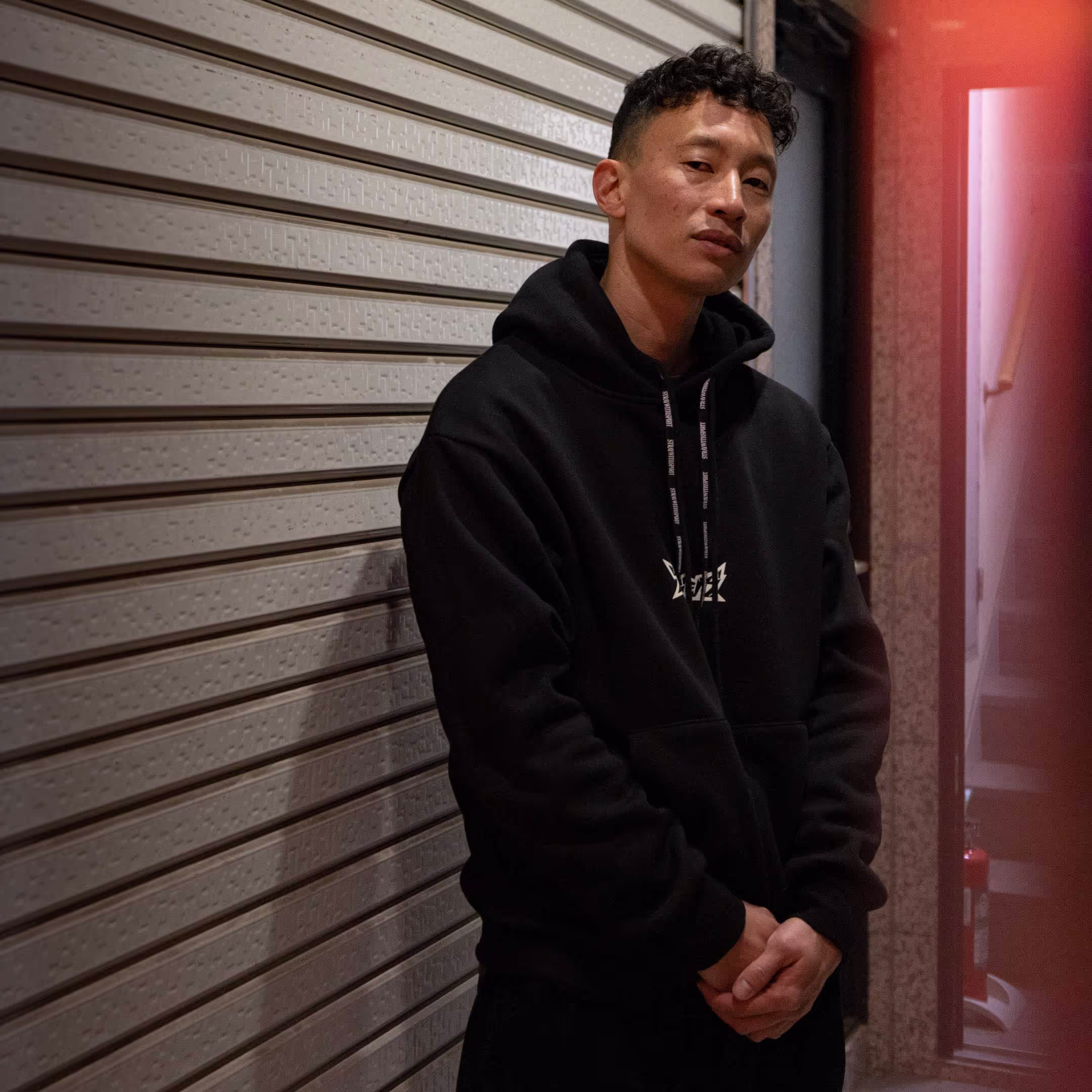 A person wearing Straygang's black "Spirit Tag" hoodie modeled on a Tokyo street.